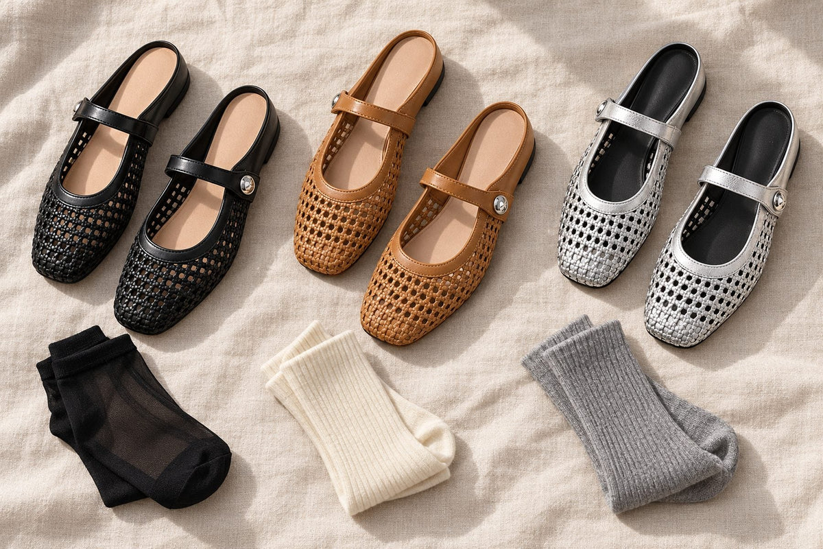 Black, camel and silver woven Mary Jane flats laid out with sheer black, cream ribbed and gray ribbed socks on linen
